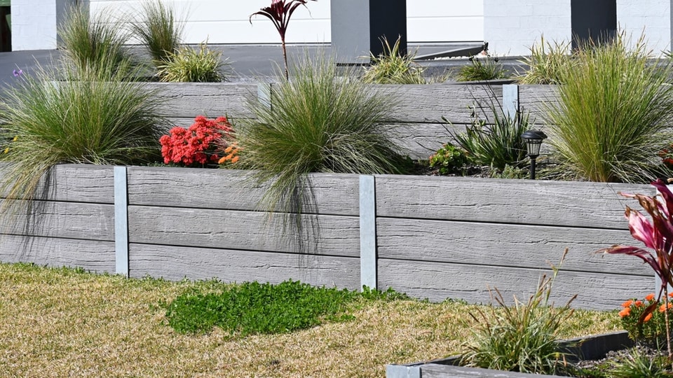 Timber-look sleeper retaining wall with steel posts and native planting in Huntley