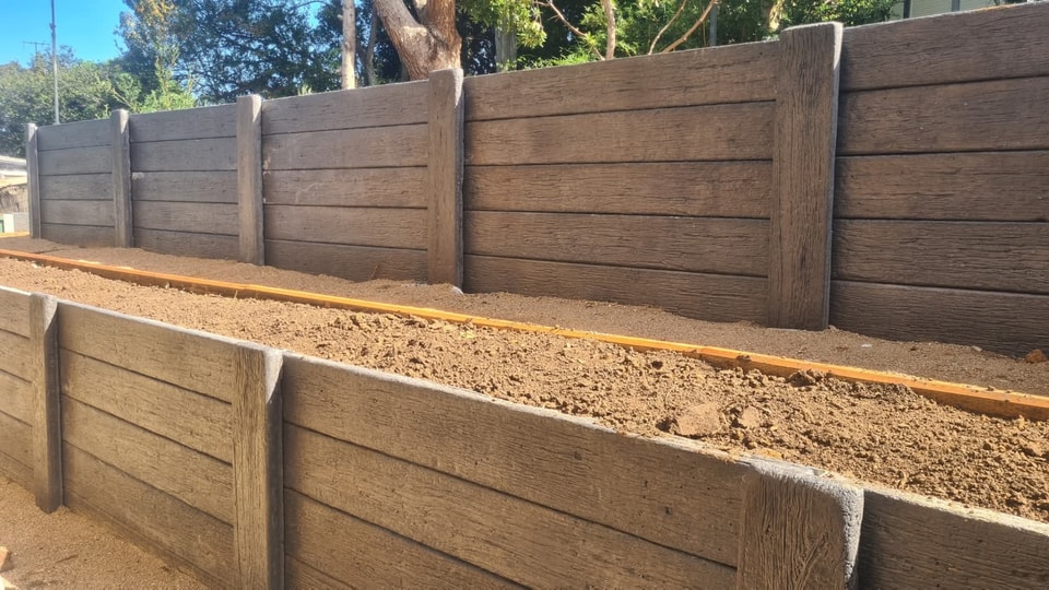 Timber-look concrete sleeper retaining walls terraced in two tiers on a Calderwood property