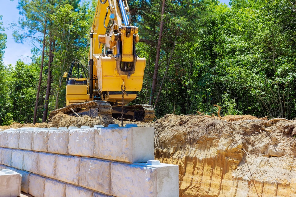 Excavator placing large concrete blocks during earthworks on a Huntley block