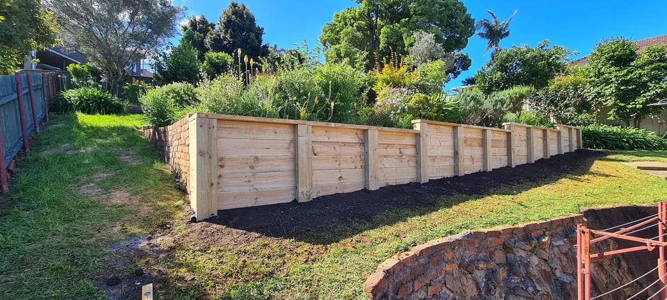 New treated timber sleeper retaining wall holding a raised garden bed in a Wollongong backyard