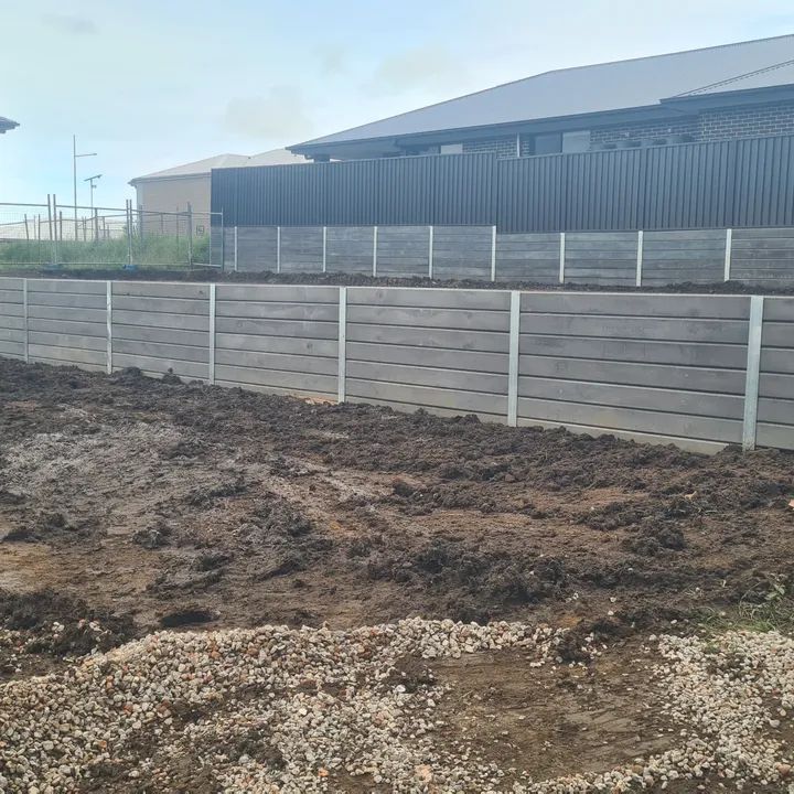 Grey concrete sleeper retaining wall with steel posts across a levelled Balgownie building site