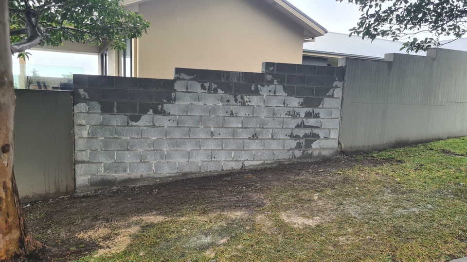 Charcoal besser block retaining wall built along a side boundary beside a Figtree home