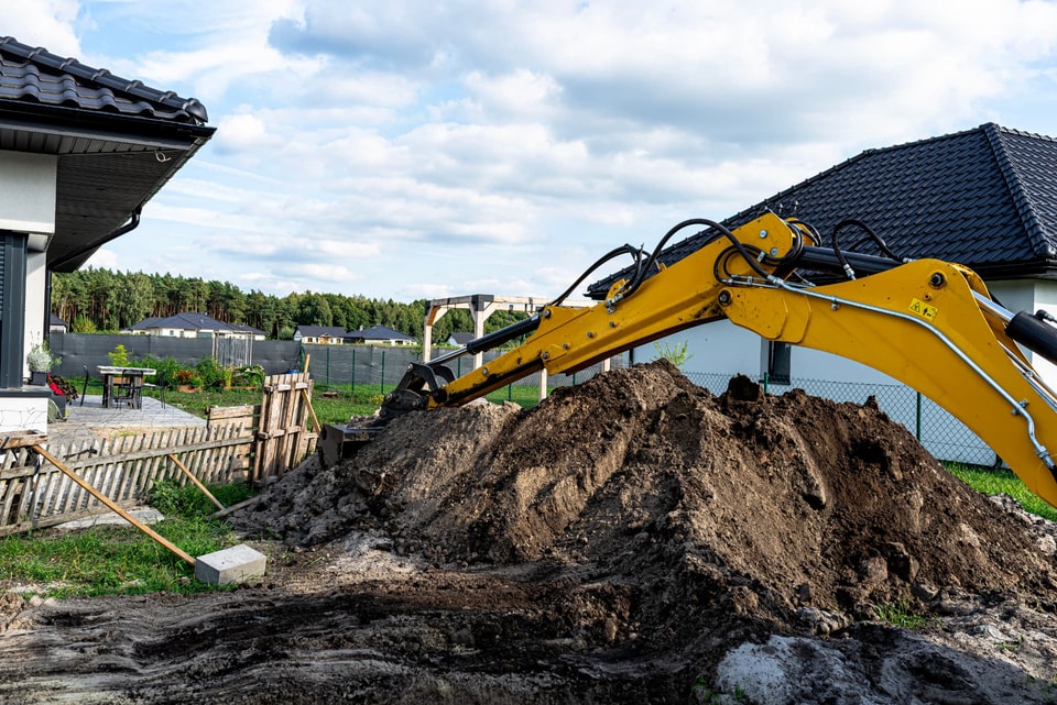 Excavator digging and stockpiling soil during earthworks at a Shellharbour home
