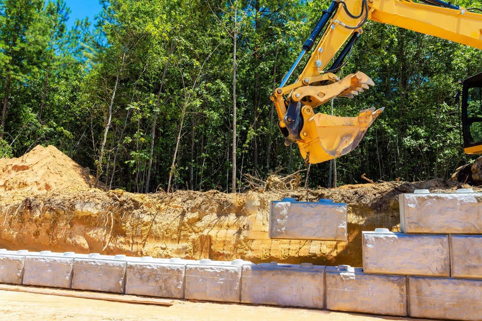 Excavator placing large concrete blocks during earthworks on a Calderwood block