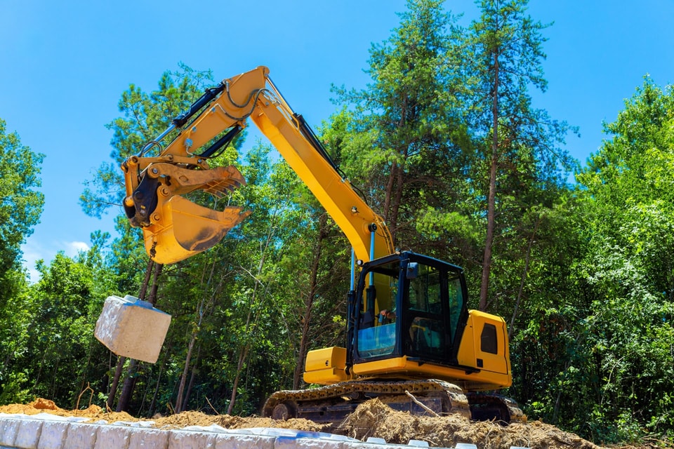Excavator lifting a large concrete block during earthworks on a Balgownie site