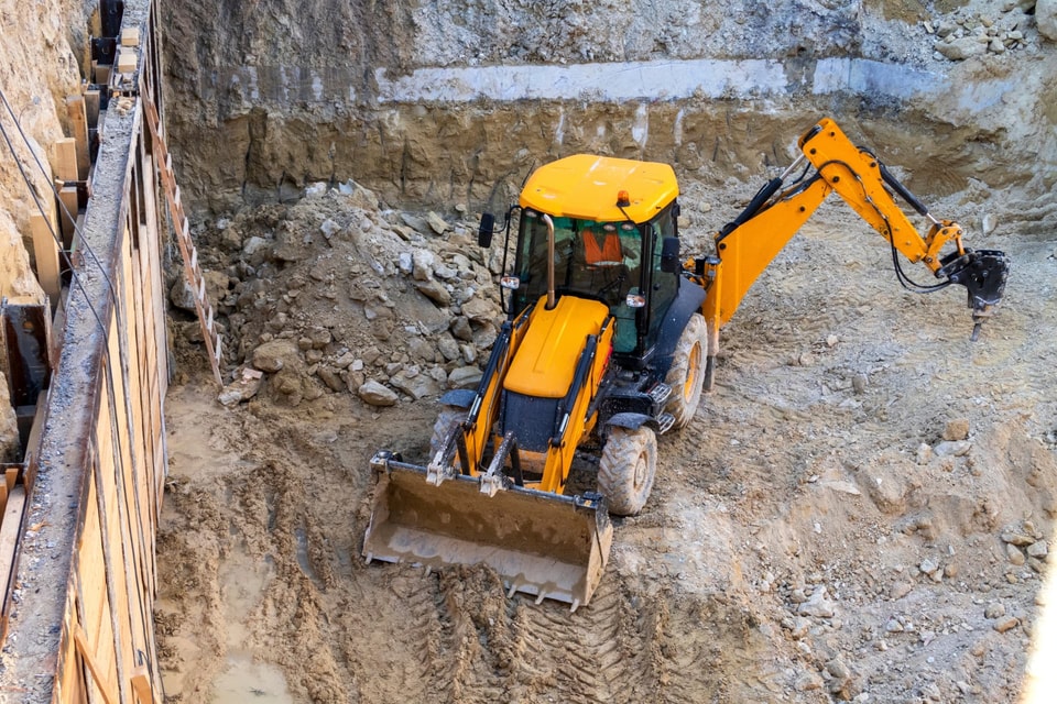 Excavator cutting a batter and shoring an excavation on a Kiama site